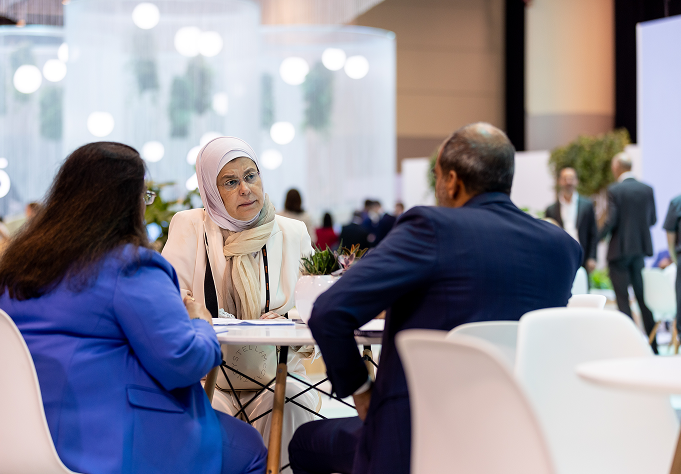 Two women talking at a table in an exhibition hall