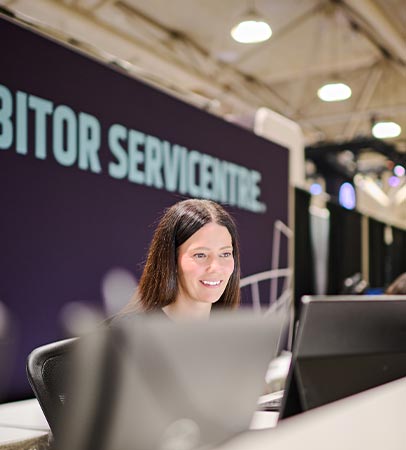 A smiling staff member at a conference visitor services desk