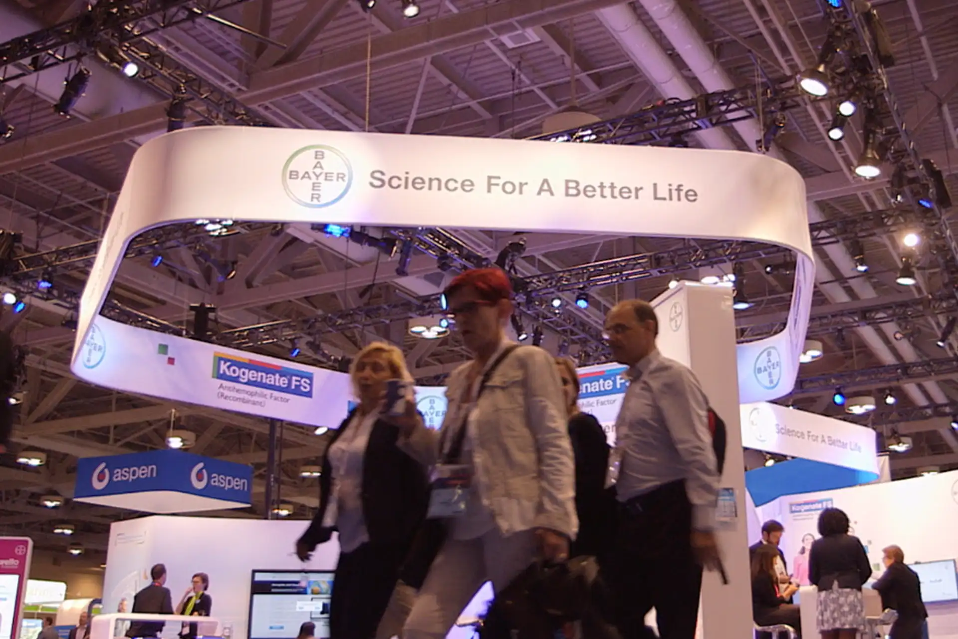 Attendees walking past a large exhibition booth at a life sciences congress