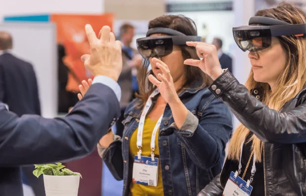 Two women trying mixed-reality headsets at a technology conference