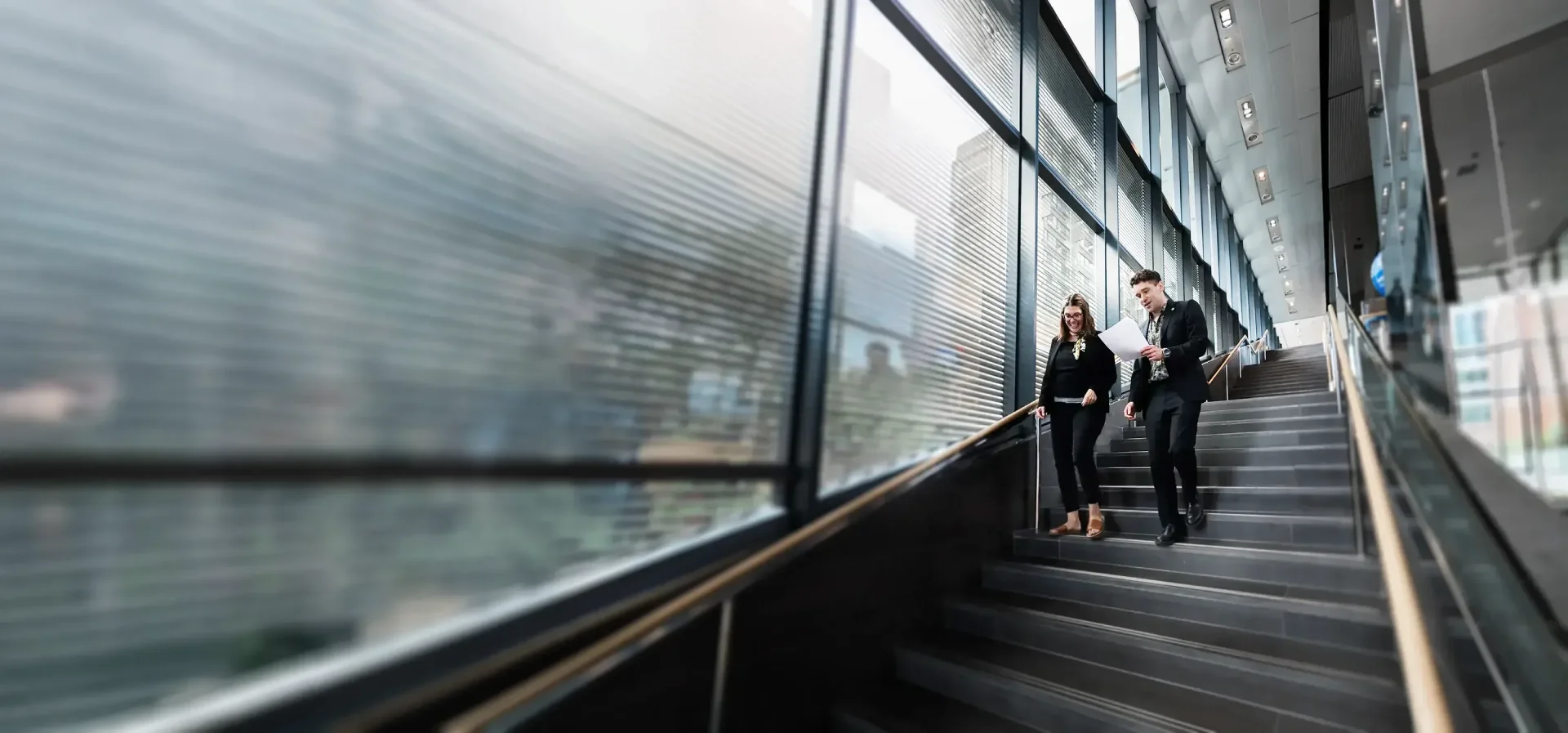 A person walking down stairs beside a large window, slightly blurred