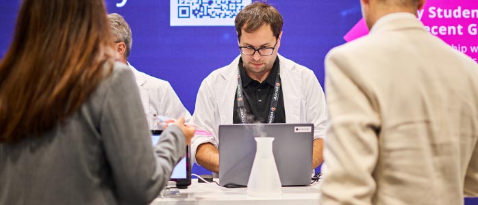 A man showing a laptop to visitors at a conference booth