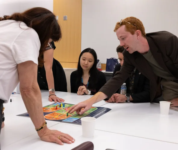 A group of people working together at a table, pointing at papers