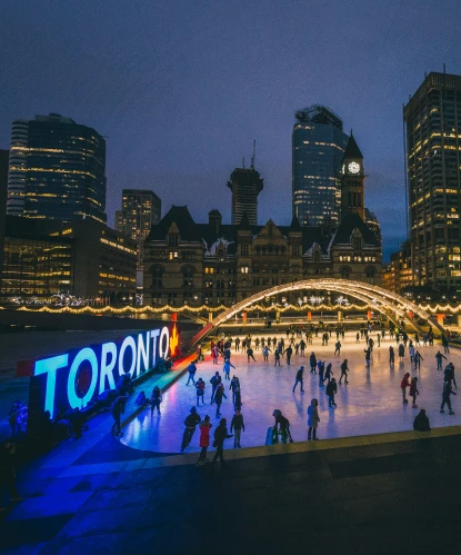 Skaters at Nathan Phillips Square at night, with the Toronto sign