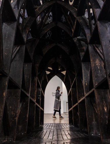 A person standing in the arched doorway of a dark, gothic building