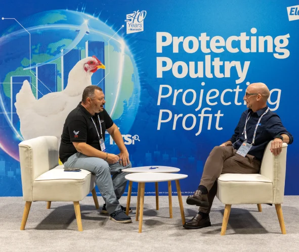 Two men talking on a stage set for a poultry science congress