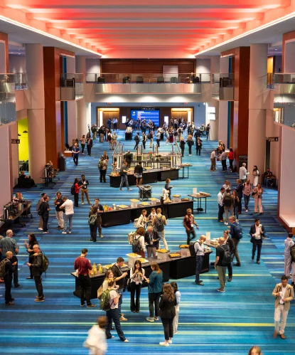 A busy conference hall with a blue carpet, seen from above