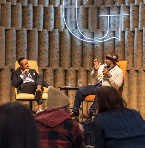 Two speakers in a panel discussion on stage, in front of an audience