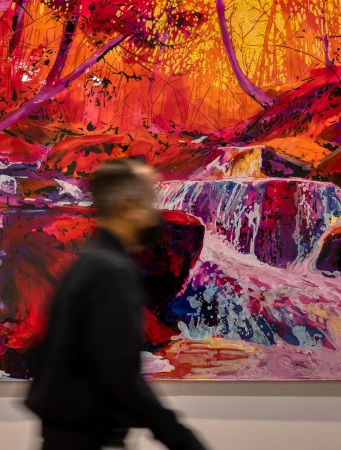 A person walking past a large, colourful abstract painting