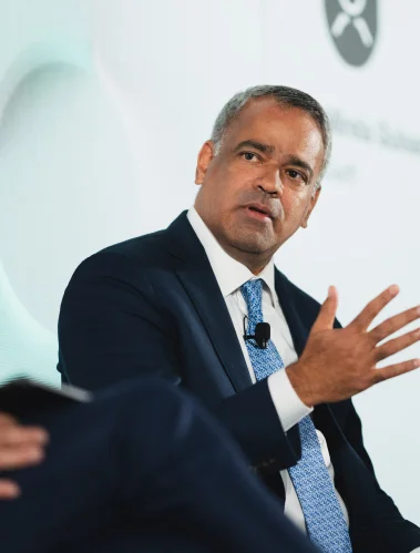 A man in a suit speaking and gesturing during an interview