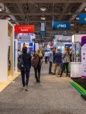 Attendees walking through a busy exhibition hall