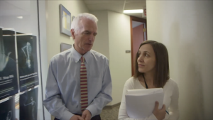 Dr. Cameron Mustard talking with a colleague in a hallway