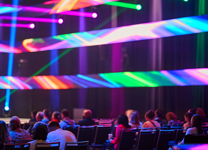 An audience under bright, colourful stage lights at a conference