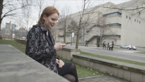 Jacqueline Bart checking her phone outside a modern building