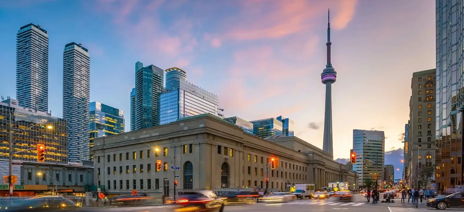 Toronto's Union Station and CN Tower illuminated against the evening sky.