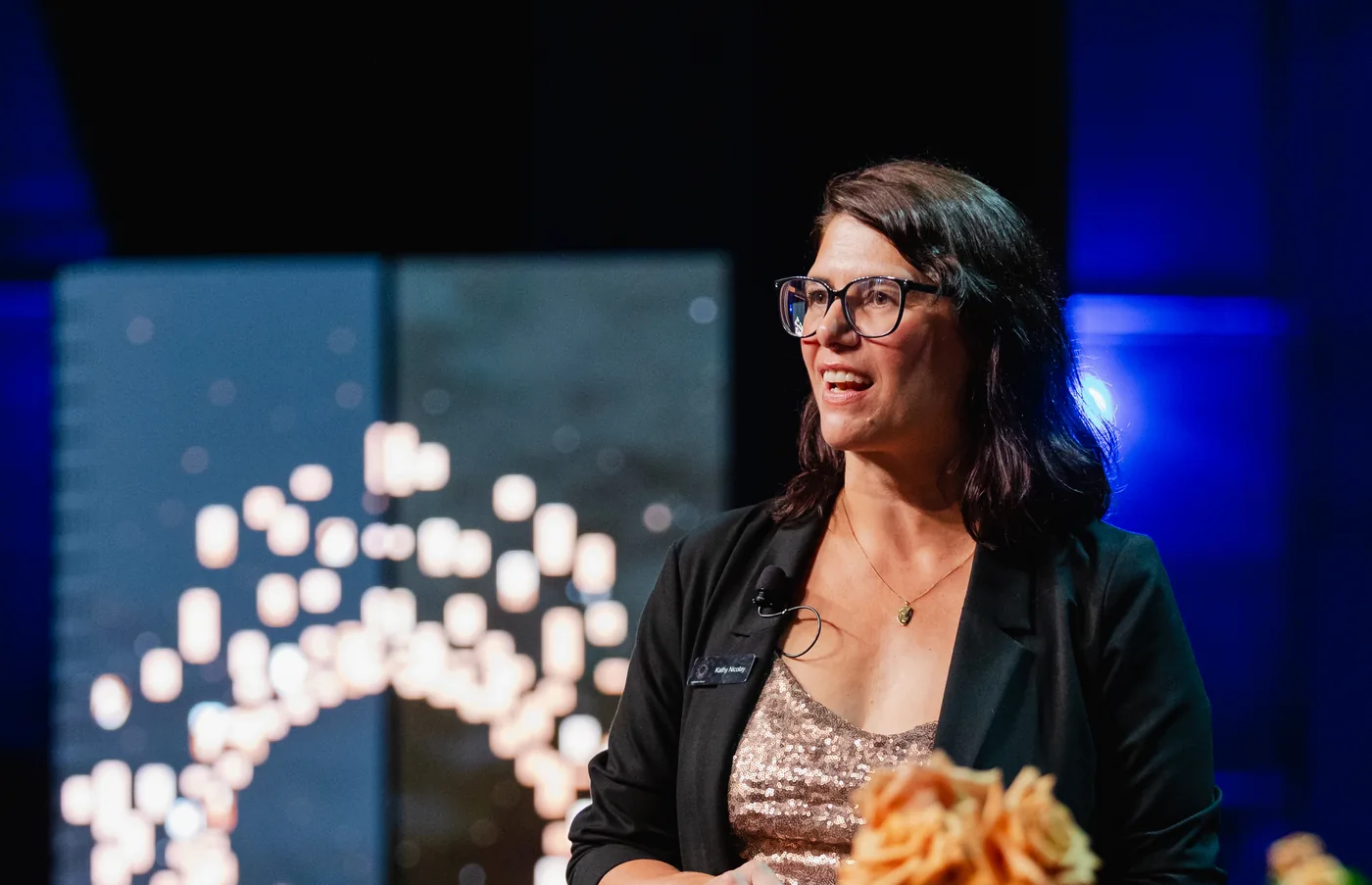 Woman speaking at a podium on stage during a formal recognition event.