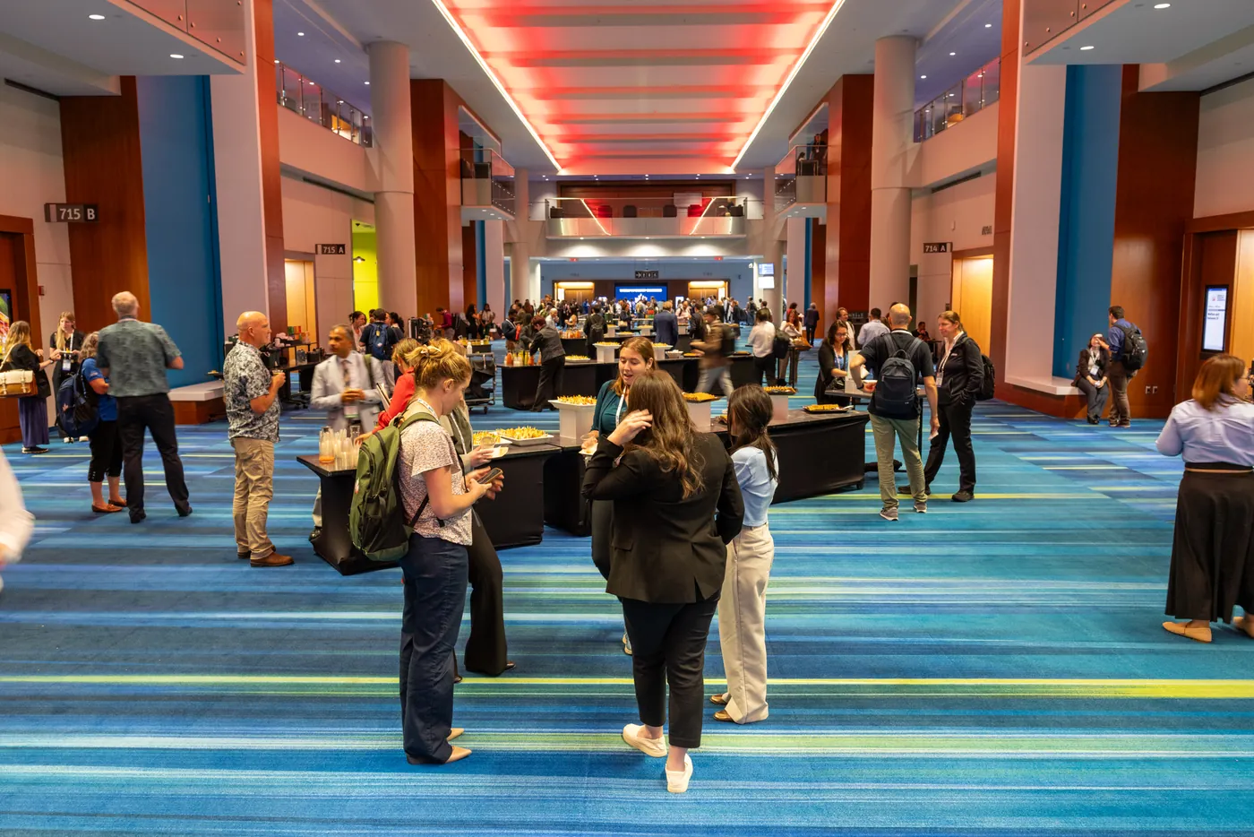 Attendees walking through a brightly lit convention centre hall.