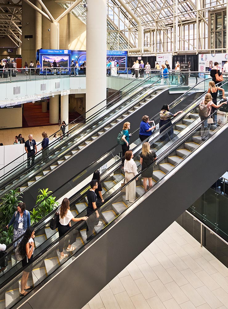 Attendees on the escalators under the glass roof of the Metro Toronto Convention Centre