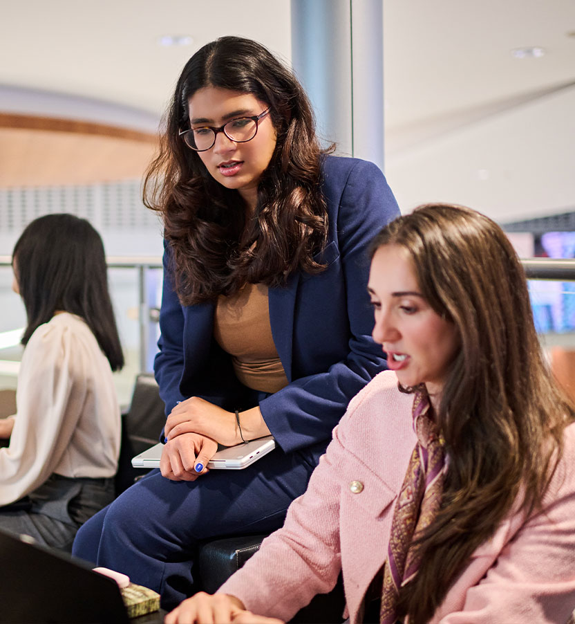 Two women looking at a laptop together at a conference