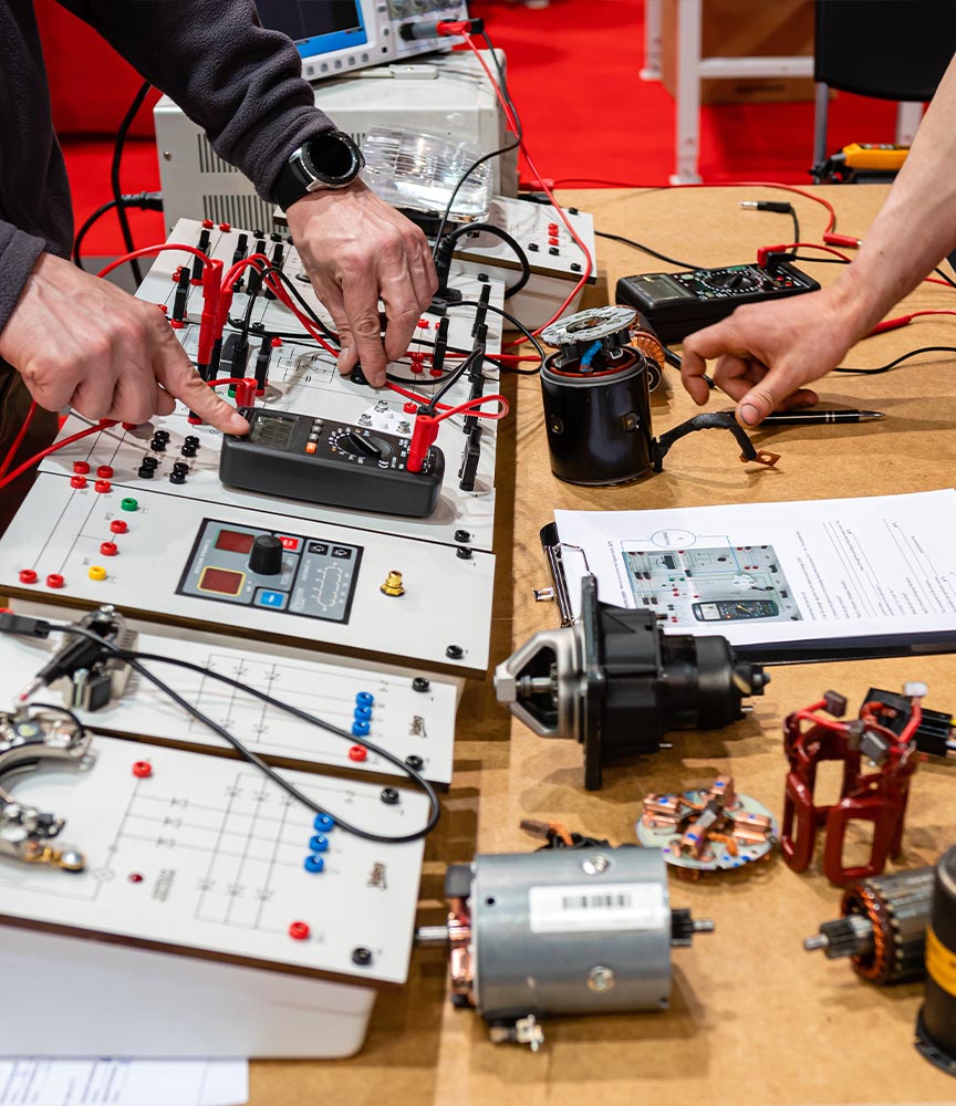 Hands working on electronic test equipment at an engineering workshop