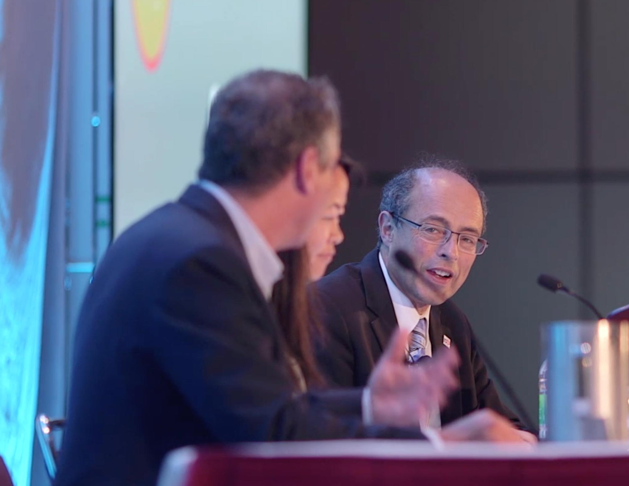 Two professionals speaking together at a podium during a medical congress.